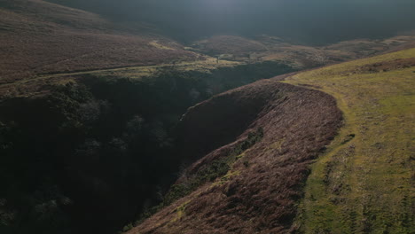 flying over gorge with hikers and reveal of misty mountain and natural lens flare in english lake district uk