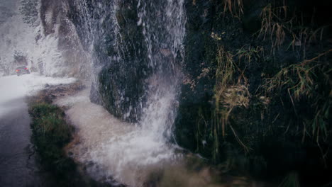 Waterfall-splashes-on-rocks-into-stream-of-icy-water-at-snowy-winter