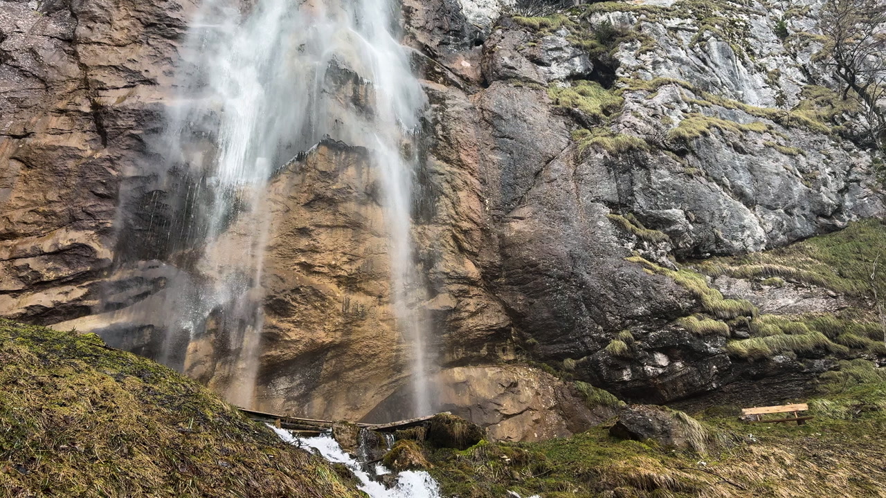 Ground-level shot starting at Skakavac waterfall and moving down to flowing mountain stream over mossy rocks near Sarajevo, Bosnia and Herzegovina.