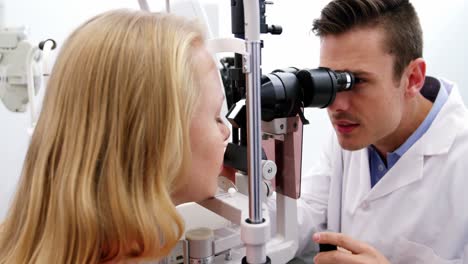 optometrist examining female patient on slit lamp