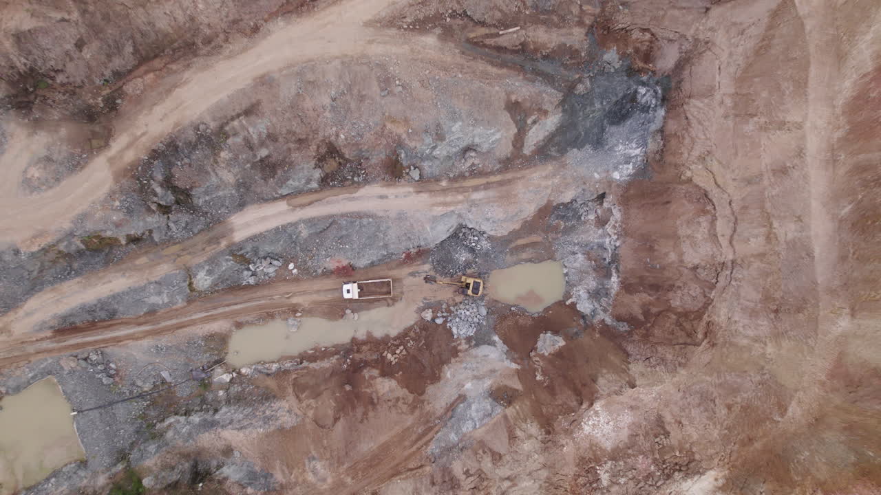 A dynamic drone shot of a excavator which empties its yield into a mining truck