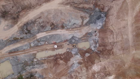 a dynamic drone shot of a excavator which empties its yield into a mining truck