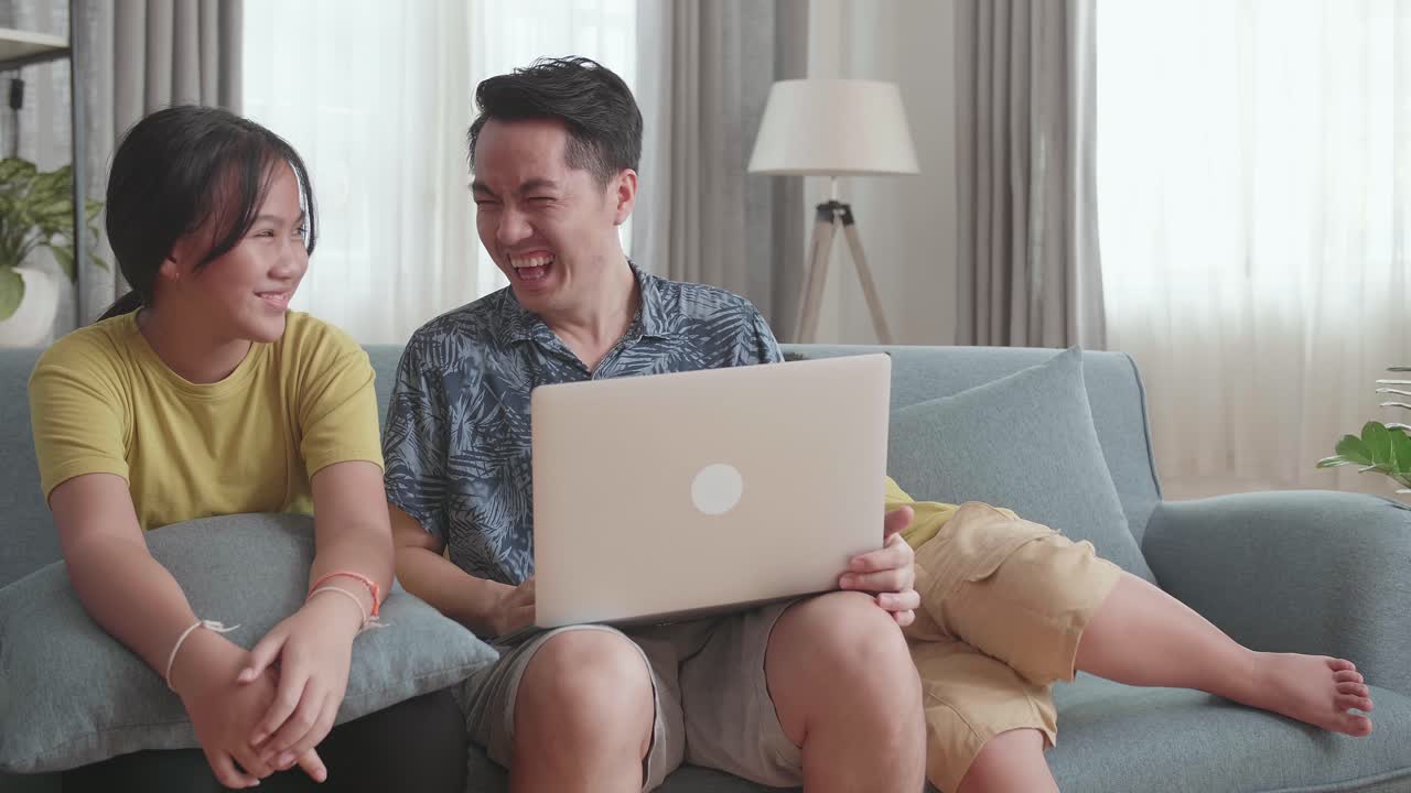 Family enjoying time together on the couch using a laptop