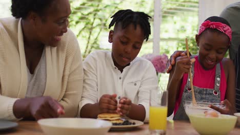 african american grandparents and grandchildren preparing pancakes in the kitchen at home