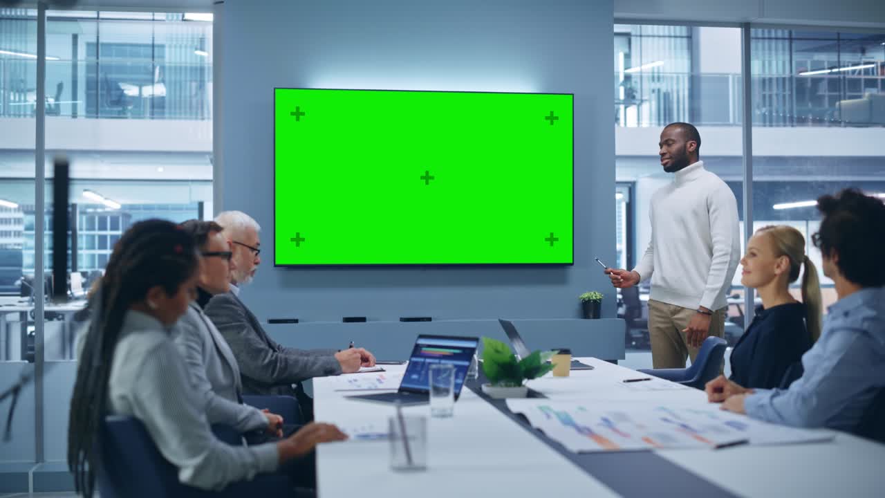 Office Conference Room Meeting Presentation: Charismatic Black Businessman Talks, Uses Green Screen Chroma Key Wall TV. Successfully Presenting a e-Commerce Product to Group of Multi-Ethnic Investors