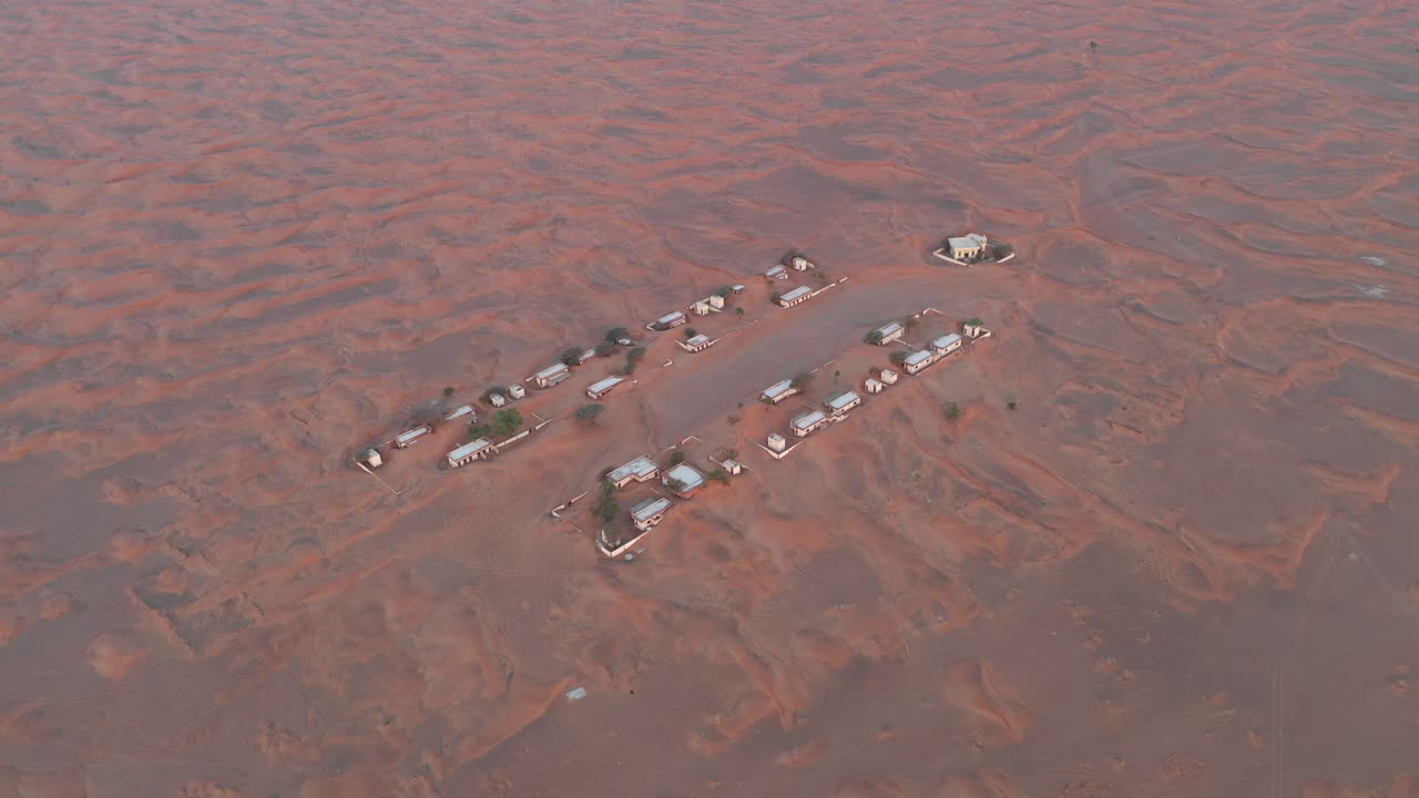 Aerial view of an empty abandoned village and homes covered in desert sand near Dubai
