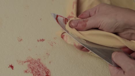 mano ensangrentada del asesino criminal que limpia la sangre de un cuchillo después de apuñalar