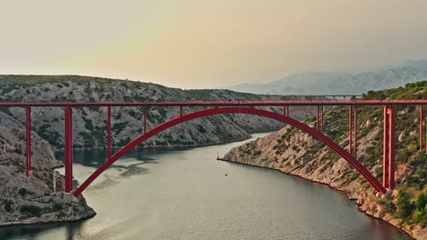 wide aerial shot of a big red bridge on a beautiful mountain scenery on sunset, vertigo effect