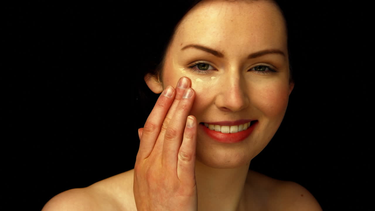 mujer sonriente aplicando crema
