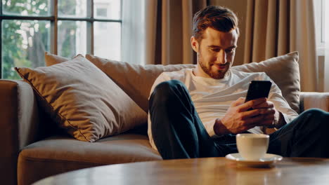 Man relaxing on a sofa and using his smartphone