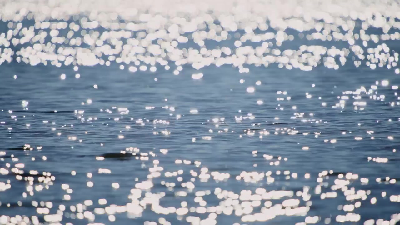 Riflessi scintillanti della luce solare sulla superficie dell'acqua blu con effetto bokeh