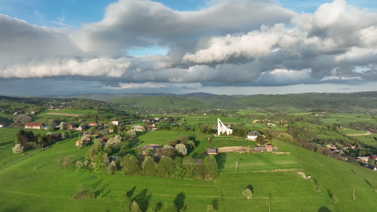 emblema de la fe: a medida que el avión no tripulado avanza, revela una iglesia moderna en la cima de una colina en una serena noche de primavera, enmarcada por nubes dramáticas contra un cielo azul claro