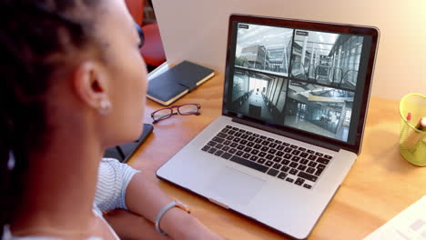oficial de seguridad afroamericana viendo negocios cámaras de cctv vistas en computadora portátil, cámara lenta