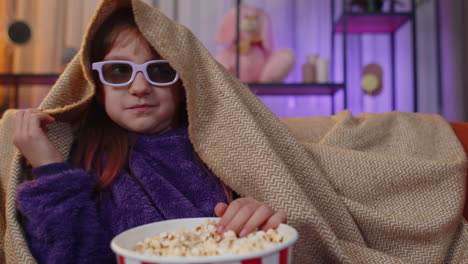 niña adolescente comiendo palomitas de maíz, viendo interesantes series de televisión, juegos deportivos contenido en línea en el sofá de casa