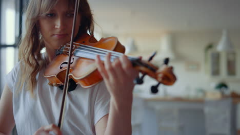 mujer enfocada tocando el violín en la sala de estar