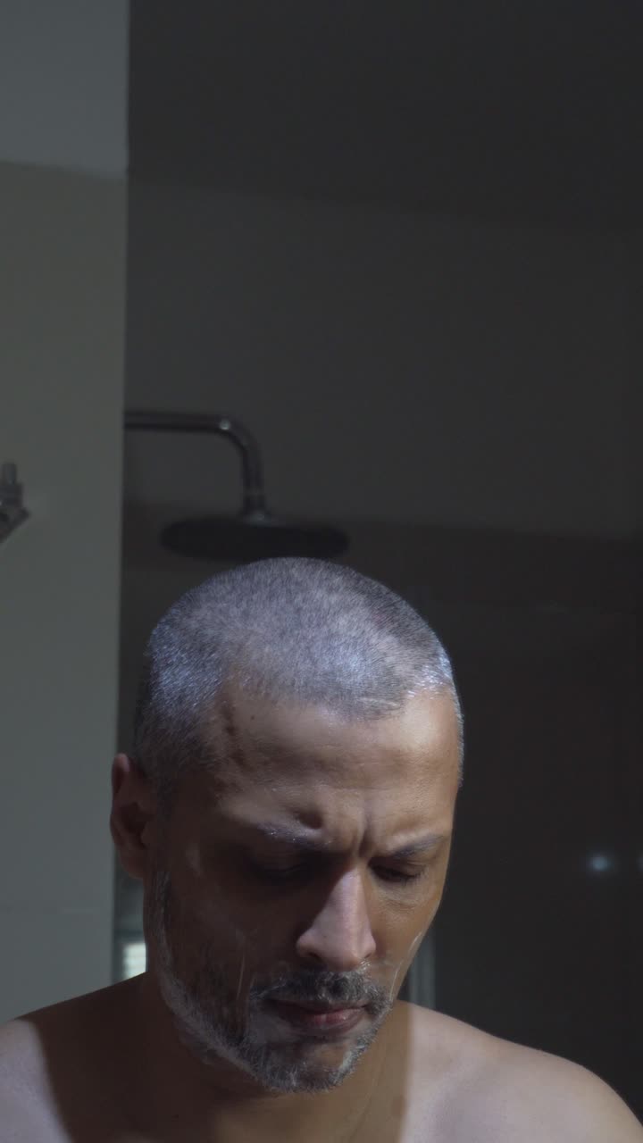 Man Shaving His Beard with a Razor in the Bathroom