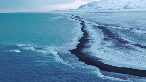 aerial panoramic landscape view over the shoreline of diamond beach, covered in snow, at dusk