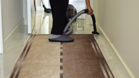 a person vacuuming a carpet in a hallway.