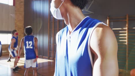 Portrait-of-african-american-male-basketball-player-wearing-face-mask-with-team