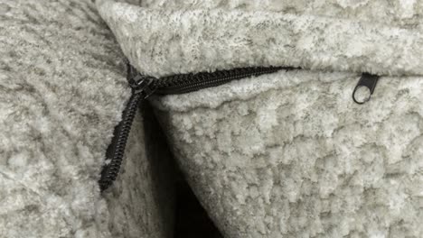 Camera-slowly-zooms-in-on-black-zipper-behind-soft-wool-cushion-on-a-sofa