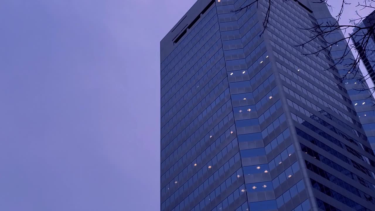 crepúsculo skyview lapso de tiempo cielo azul púrpura en el centro de la ciudad reflejo reflejado de edificios en capas con movimiento de nubes y árbol ramificado desnudo ondulado en un otoño invierno ventoso frío final del día de trabajo