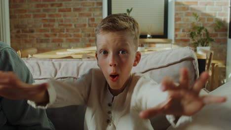 a boy looking happy and surprised on a couch