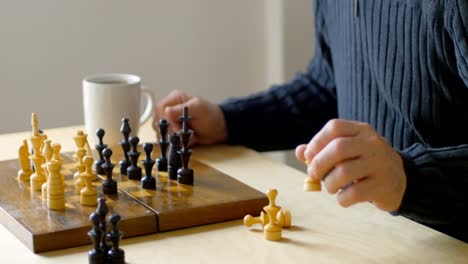 hombre jugando al ajedrez mientras toma café en la sala de estar