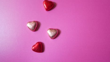 decorative shiny foil wrapped love heart shaped sweet candy stop motion pink colourful background