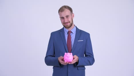 portrait of happy bearded businessman with piggy bank