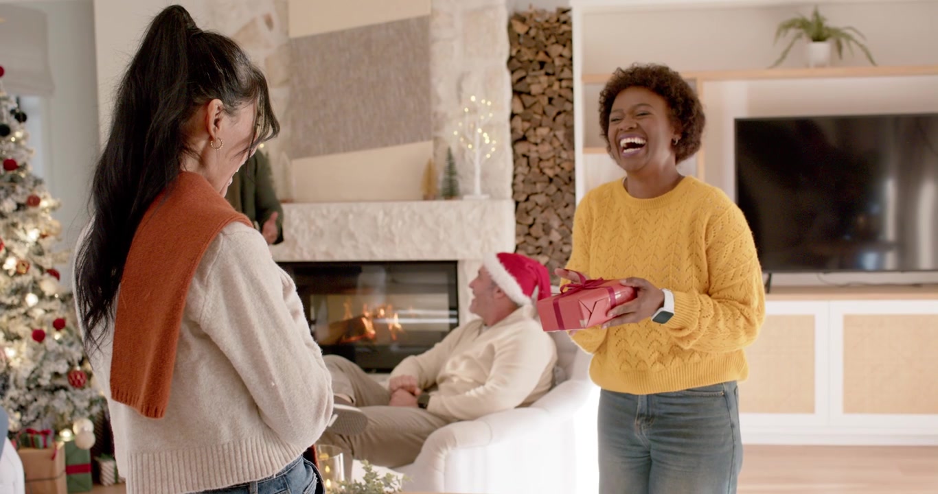 Donna felice che dona un regalo di Natale a un'amica in salotto