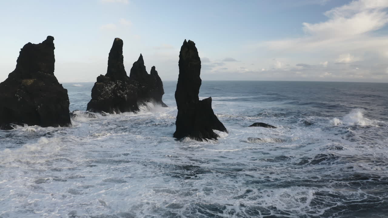 vista aérea pasando por escarpadas rocas de reynisdrangar, en la costa de la soleada islandia