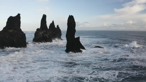 aerial view passing steep reynisdrangar rocks, on the coastline of sunny iceland