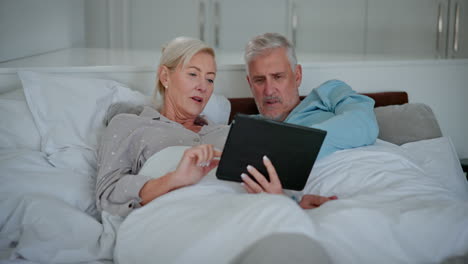 couple using tablet in bed