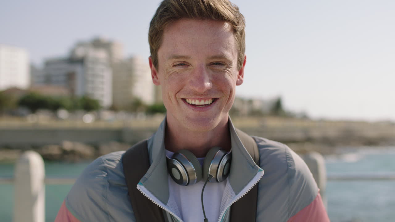 nærbildeportrett av munter ung mann smilende og glad på solfylt strand
