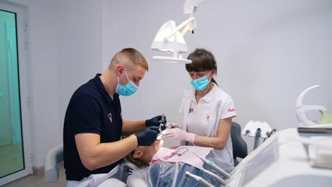 dentist and patient in dentist office. doctor in uniform checking up female patient teeth in dental clinic
