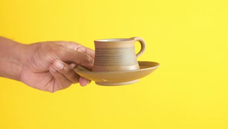 hand holding a small coffee cup and saucer