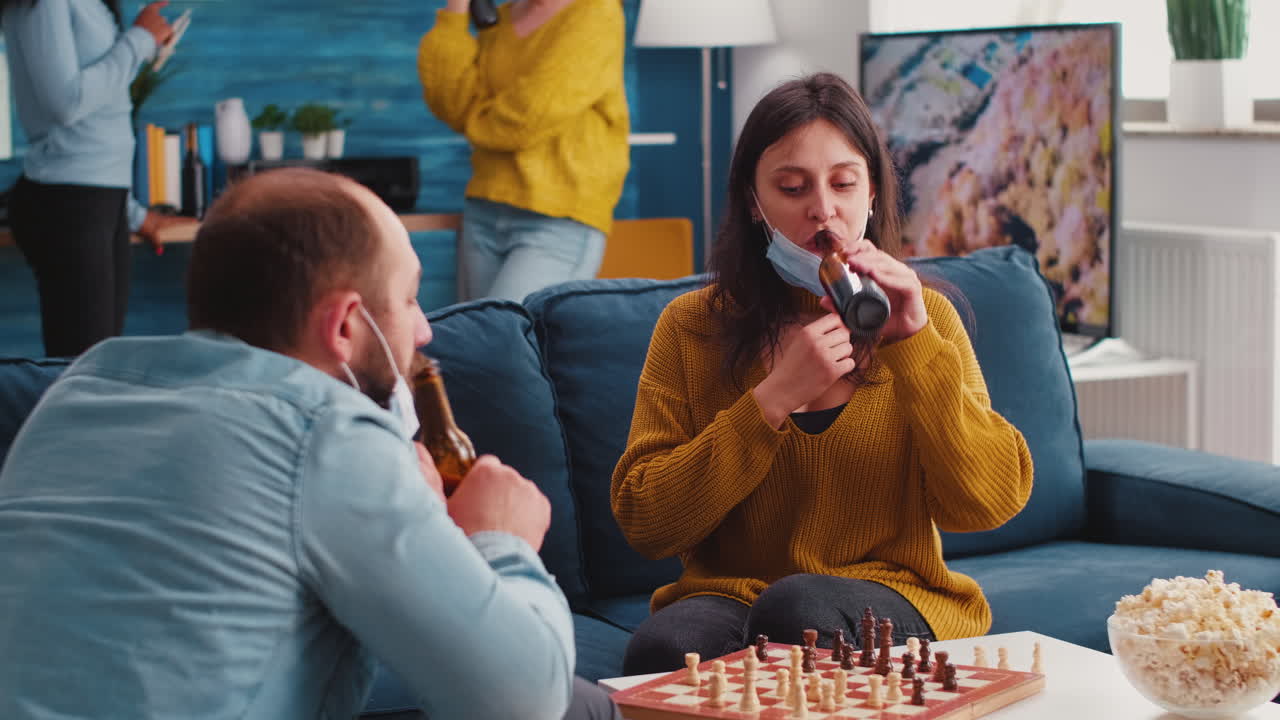 Friends having fun playing chess in living room during global pandemic
