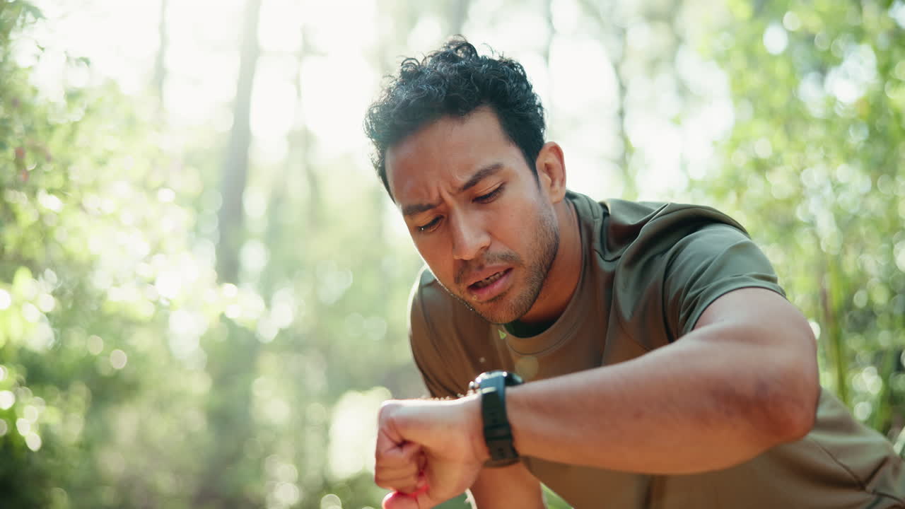 Tired Male Runner Resting and Checking Smartwatch in Forest