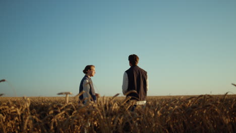 Agricultural-partners-discussing-harvesting-season-at-golden-sunset-wheat-field.