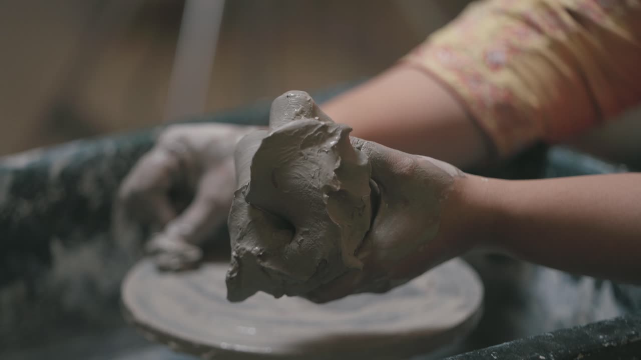 Closeup shot of hand covered during in wet clay during pottery.