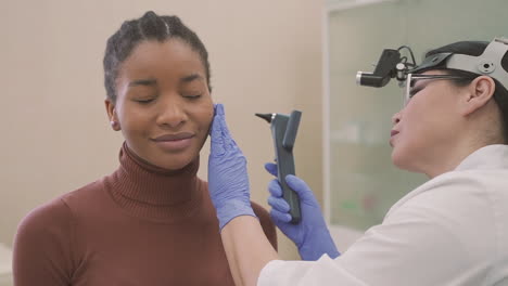 médica fazendo uma verificação auditiva no ouvido de um paciente, uma jovem