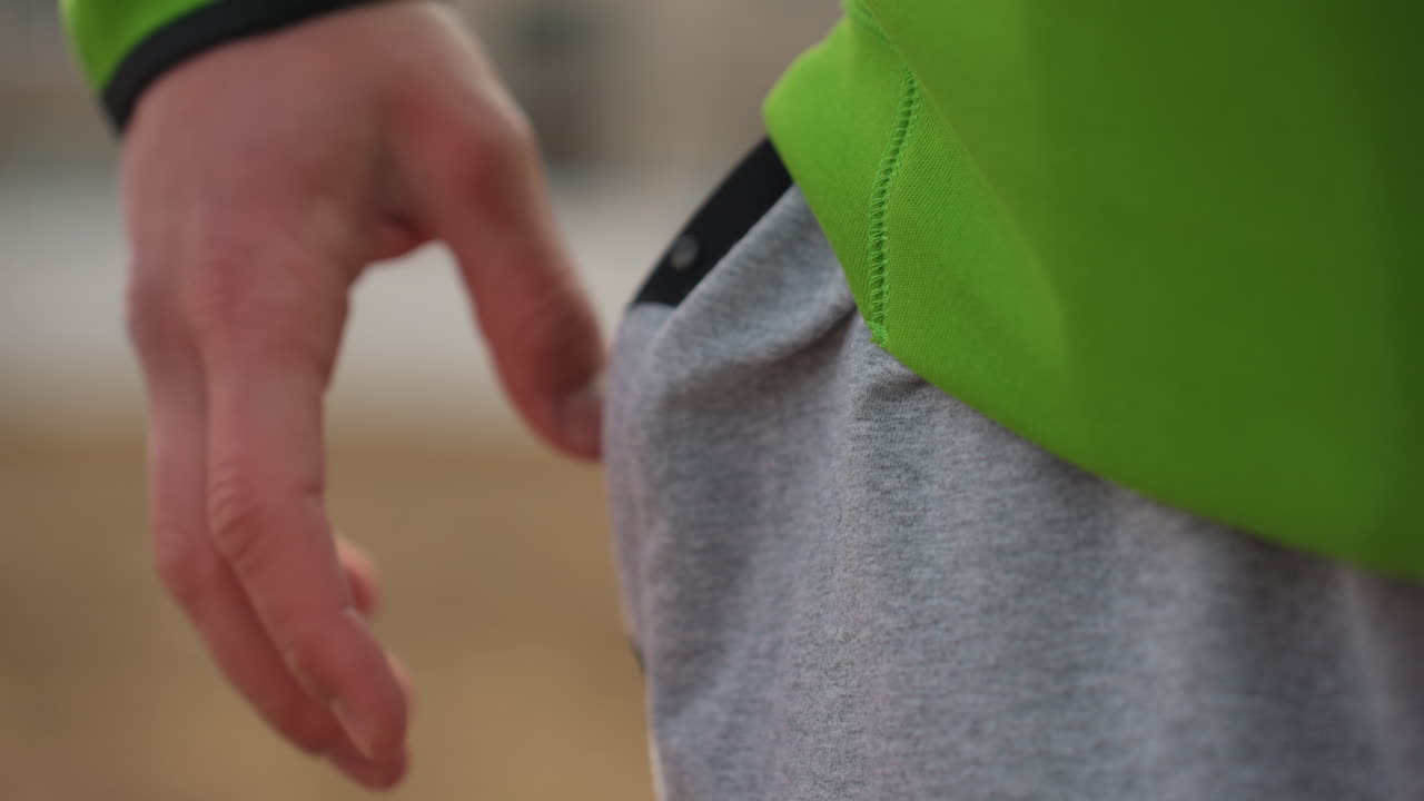 pants pocket grab, closeup of pocket opening outdoors, fingers reaching mobile phone from sweatpants pocket, closeup of hands retrieving mobile device from sweatpants pocket while outdoors