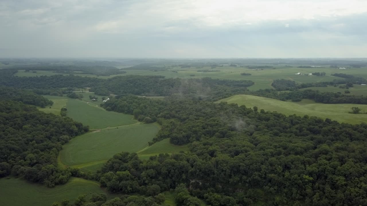 Aerial shot flying through misty clouds over Iowa farmland, America