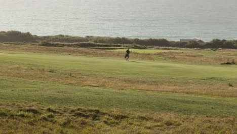 static shot of a golfer walking across the course to head to play his ball