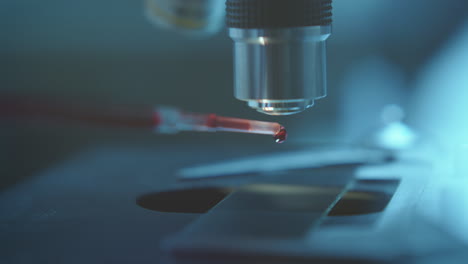 dripping blood onto glass slide on microscope stage for medical testing