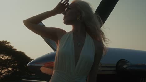 woman in a dress near an airplane at sunset