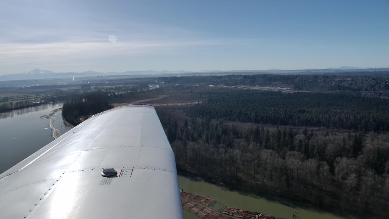 avión volando sobre el bosque y el río, vista del piloto en el ala izquierda