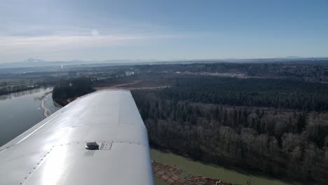 Avión-Volando-Sobre-El-Bosque-Y-El-Río,-Vista-Del-Piloto-En-El-Ala-Izquierda