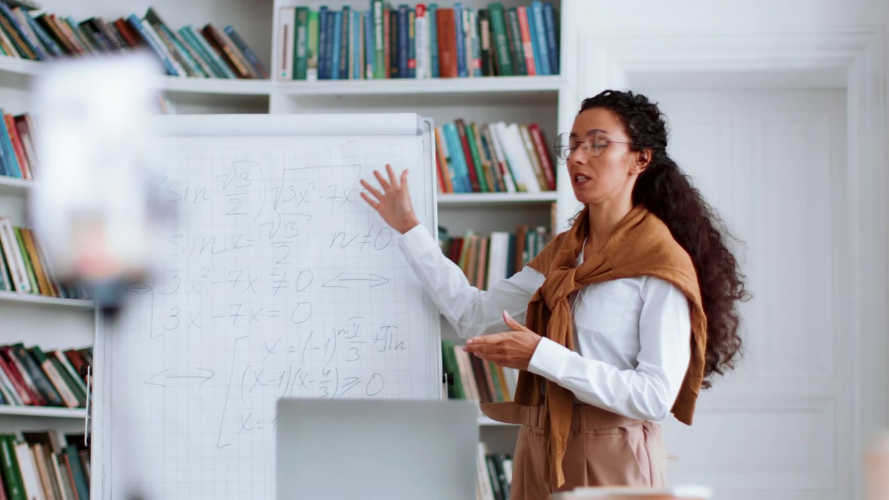 Insegnante donna che spiega matematica alla lavagna in biblioteca