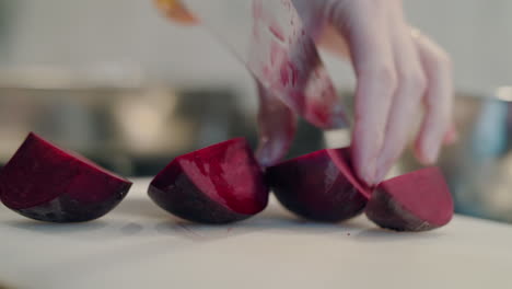 a woman chef carefully and expertly cuts vibrant beetroot into sectors in her clean kitchen. healthy vegetarian cooking concept.